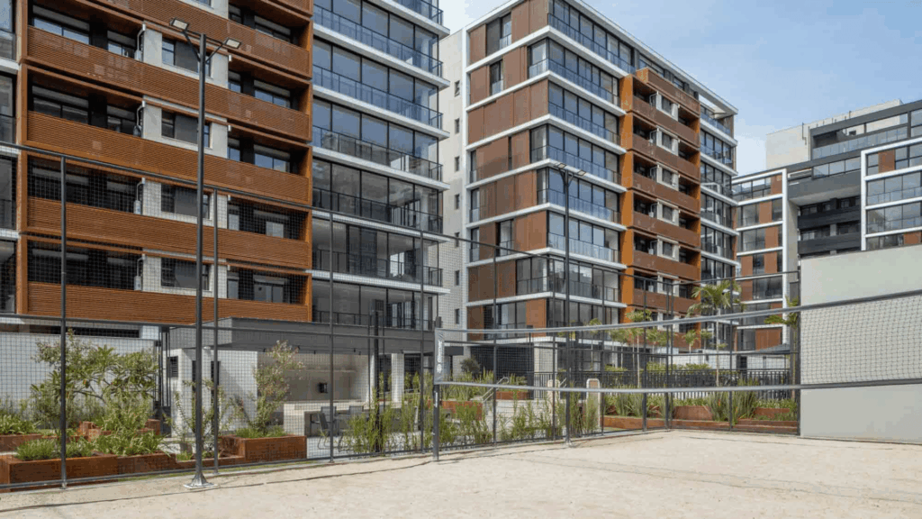 Quadra de areia em condomínio residencial moderno com prédios ao fundo.