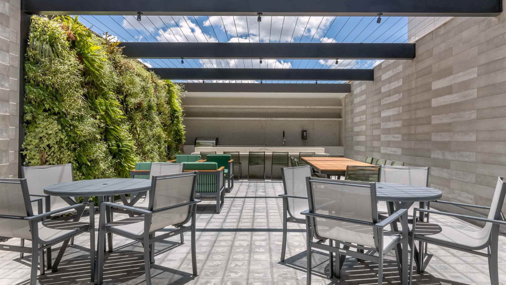 Espaço semiaberto no Park Sul Brasília com mesas, cadeiras e plantas ao redor, oferecendo um ambiente aconchegante e integrado à natureza para momentos de lazer e convivência.