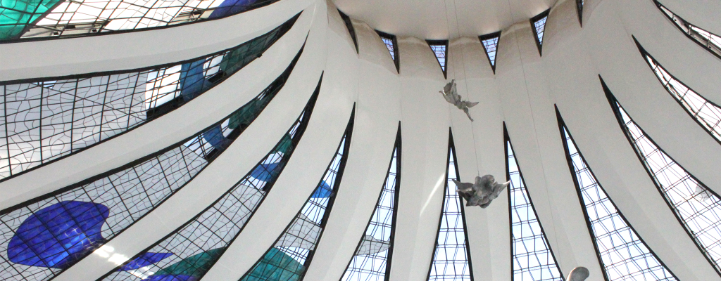 Imagem da arquitetura moderna de Brasília. Uma cúpula com desenhos de pássaros e vitrais coloridos.