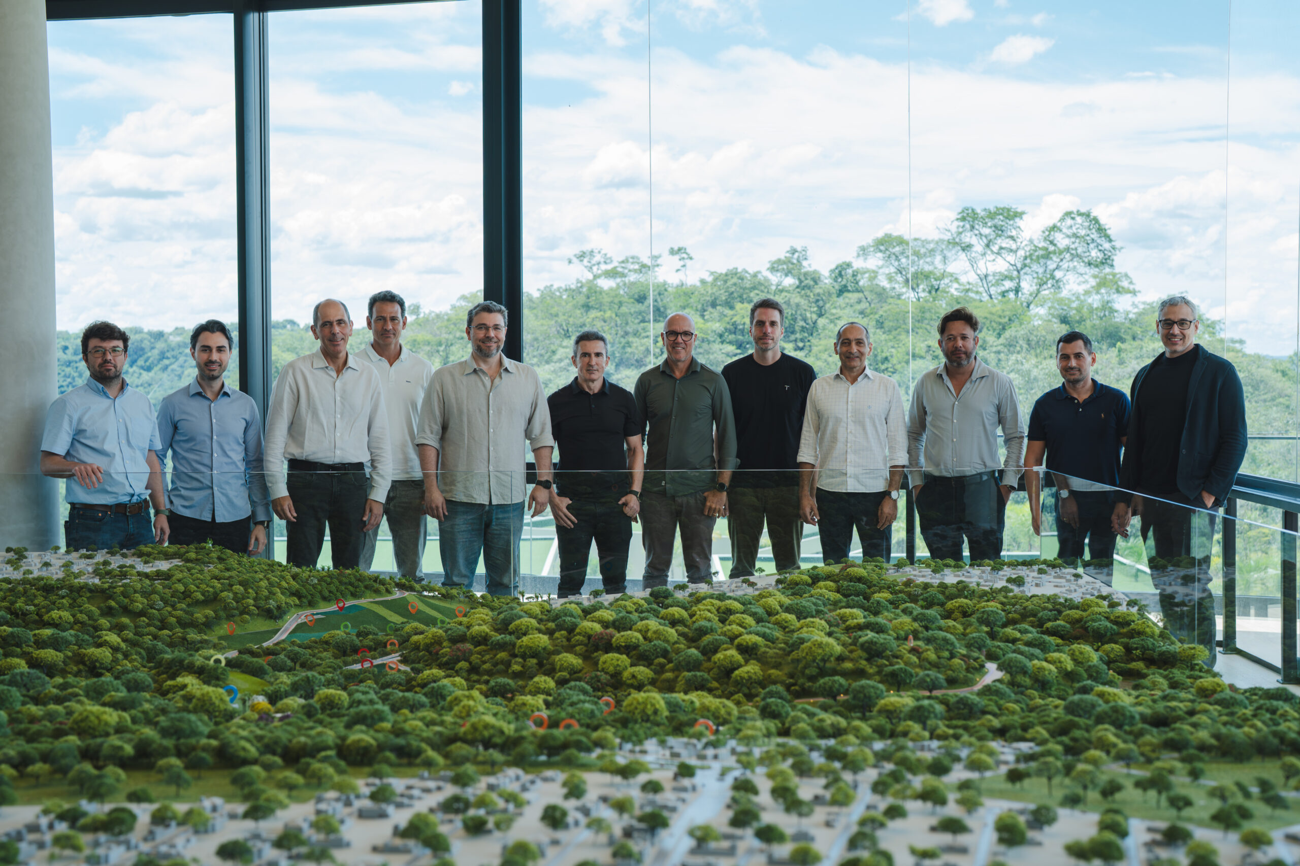 Membros do Reserva Jardim Botânico juntos a Membros do Terral próximo a uma maquete do parque.